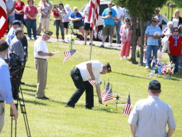 Image of a memorial Day program at the cemetery. Veterans are placing flags for deceased veterans.